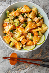 Asian Rojak salad with cucumber, pineapple, peanuts and fried tofu seasoned with sweet and spicy sauce close-up in bowl on table. Vertical top view from above