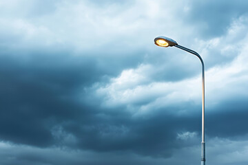 Street lamp illuminates dark sky filled with dramatic clouds, creating moody atmosphere