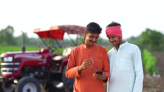 two young indian farmer using smartphone together at agricultural field	