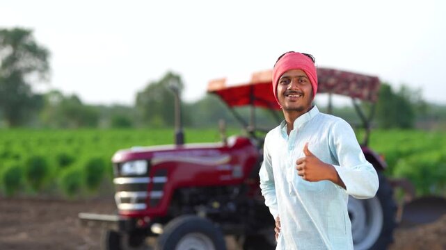 young Indian farmer showing thumps up with new tractor 