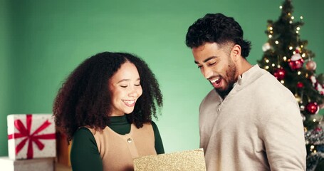 Christmas, opening and surprise with couple in studio together for reaction to gift or present. Box, festive or wow with man and woman on green background for celebration, holidays or tradition - Powered by Adobe