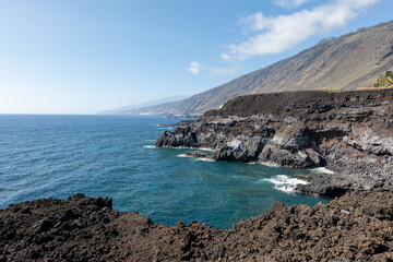 Dramatic volcanic coastline in southern La Palma, with cliffs, dark rocks and blue ocean.