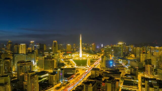 Johor bahru skyline featuring the brightly lit millennium monument at the city center, surrounded by illuminated buildings and busy roads during dusk, creating a captivating urban nightscape