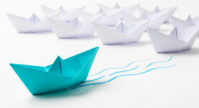 Blue paper boat leads white fleet, symbolizing leadership, innovation, and unique path to successFree space for text