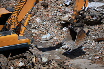 Excavator stands on rubble of house. Dismantling process, demolition of old building, destruction...