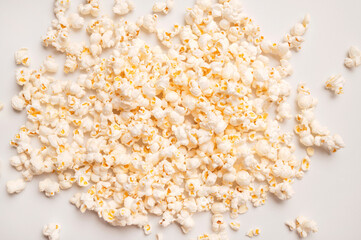 Scattered salty or sweet popcorn on light gray background top view. Corn flakes, food for movie or cinema. Delicious appetizer, party snack. Empty space for text, advertising