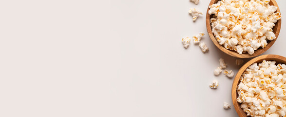 White salty or sweet popcorn in wooden bowl on light gray background, top view flat lay. Corn flakes, food for movie or cinema. Delicious appetizer, party snack. Empty space for text