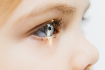 Obraz premium Close-up of a child's eye showcasing detailed iris and eyelashes, with soft lighting illuminating the eye, emphasizing vision health and the importance of regular eye examinations for children