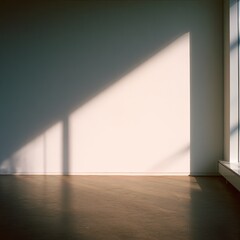 Empty room with sunlight casting a diagonal shadow on a pale wall. Sunlight streams through a large window, illuminating a simple interior space
