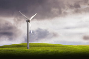 Obraz premium Wind turbine slowly rotating on a green hill, dramatic sky in background, clean landscape with minimal visual noise