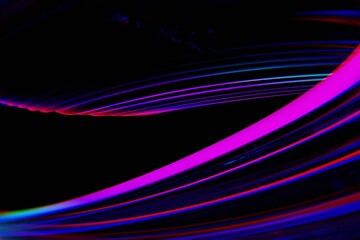 Abstract swirling lines of vibrant fuchsia, blue, and red light trails on a black background