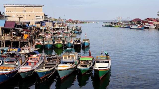 A row of traditional fishing boats lined up neatly in the Manggar fishing village in the afternoon with a calm atmosphere