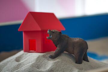 The concept of psychology. Sand
therapy. A bear figurine on
the background of a red house, in a blue
sandbox. Psychology. Therapy. PTSD
