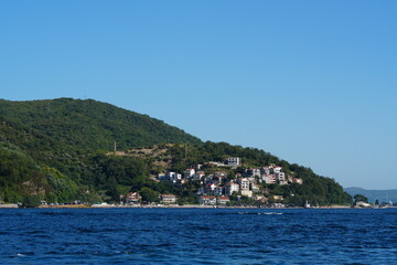 Picturesque coastal village on a green hillside by the Bay of Kotor, Montenegro, on a sunny day