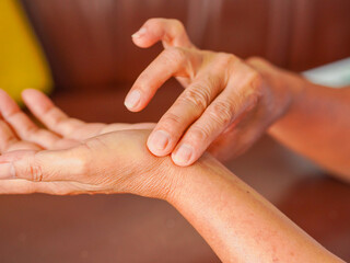 Close-up elderly woman hand taking her pulse on upper arm, senior pulse measurement. Healthy lifestyle people healthcare. Home care. Patient 