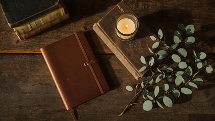 Leather journal with candle and eucalyptus branch on rustic wooden table