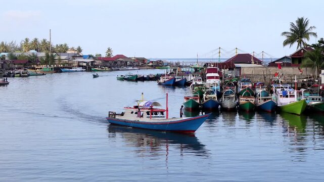 Traditional fishing activities using wooden boats on the Manggar River with a background of a row of boats anchored in the fishing village in the afternoon