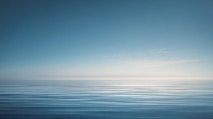 Fototapeta premium A calm, vast ocean under a clear blue sky with soft clouds and gentle sunlight reflecting on the water surface.