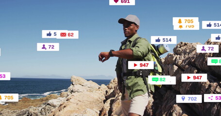 Checking smartwatch male hiker exploring rocky shore with backpack, social media icons, copy space