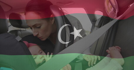 Leaning father securing harness straps in rear seat of sedan, with seat belt, headrest and window