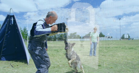 Holding bite sleeve, trainer in padded suit bracing German Shepherd biting on field, training blind