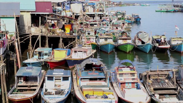 A row of traditional fishing boats lined up neatly in the Manggar fishing village in the afternoon with a calm atmosphere
