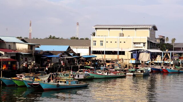 A row of traditional fishing boats lined up neatly in the Manggar fishing village in the afternoon with a calm atmosphere