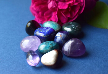 Amethyst, lapis lazuli, apatite crystals and rose flowers on blue background.