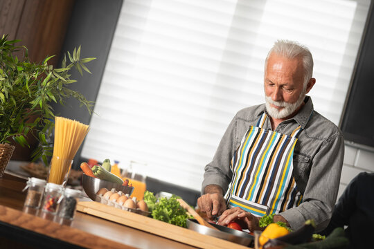 Happy senior man cooks with pleasure