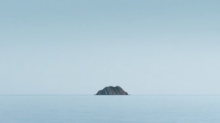 A small rocky island sits peacefully in a vast, calm sea under a clear, pale blue sky.