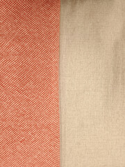 A close-up comparison of two distinct fabric swatches, one textured orange and one plain beige.
