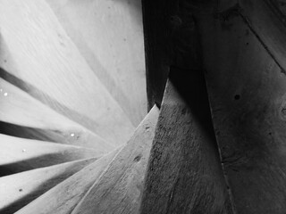 black and white photograph of a wooden spiral staircase looking downwards with shadows and bright illumination