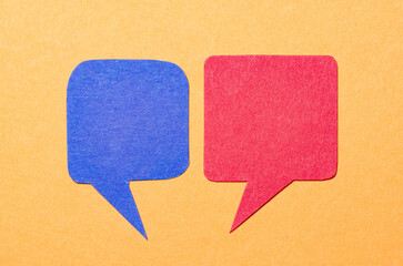 Blue red blank cut out paper speech bubbles with copy space for text on orange background, flat lay top view conceptual conversation backdrop
