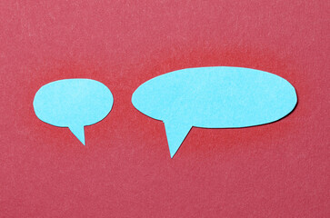 Blue blank cut out paper speech bubbles with copy space for text on red background, flat lay top...