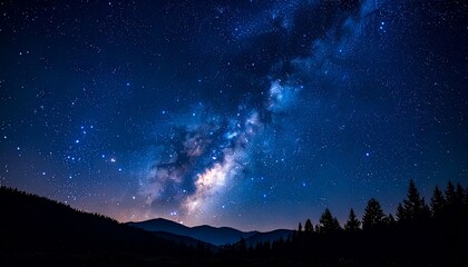 Fototapeta premium Starry Sky above hills A vibrant Milky Way arcs across a dark blue night sky above silhouetted tree-lined hills