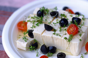 Feta cheese with olives, tomatoes and microgreens.