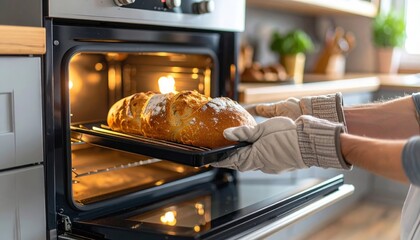 Baker taking freshly baked bread out of oven