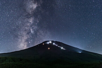 富士山の林道から登山者の光跡と富士山頂にそびえたつ天の川