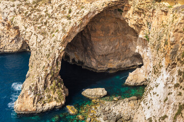 Cliff arch and blue waters at Blue Grotto in Malta.