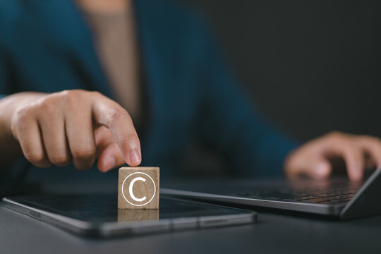 Man touching wooden block with copyright icon for author rights and patented intellectual property. Copyleft trademark license. Copyright or patent concept.