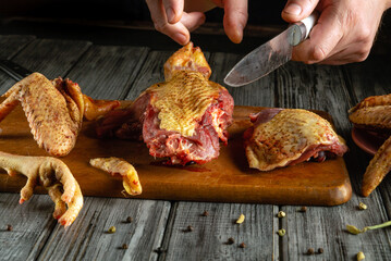 Chefs are carefully cutting raw duck and chicken pieces on a wooden board, showcasing the preparation of a traditional culinary dish in an inviting kitchen environment