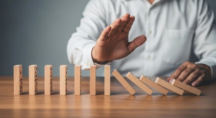 Risk management or intervention concept shown by hand halting half-fallen dominoes