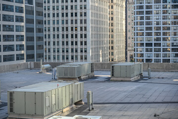 Rooftop view of air conditioning units with urban skyline in daylight