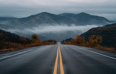 Naklejka premium Empty road stretching into a misty mountain range in autumn