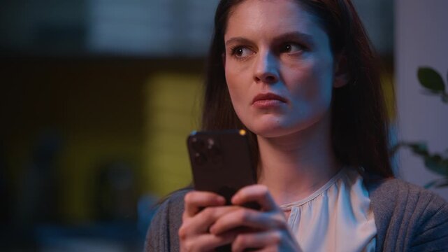 Angry woman irritated Caucasian girl texting message mobile phone chatting online social media chat messaging annoyed furious female using smartphone at night evening home negative emotions typing sms