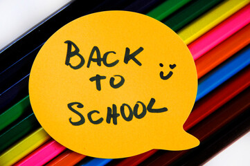 Colored pencils diagonally, and a label or emoji above it written back to school and a happy face drawn next to it