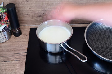 Cooking polenta porridge — a pot of milk heating on the stove while a cook sprinkles dry polenta into it.