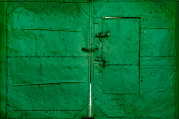 weathered green metal doors with vintage latches and hinges showing, patina and age. Industrial gate detail with distressed paint and authentic wear patterns.