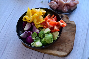 Top-down view of a bowl filled with freshly chopped vegetables, set against the background of meal preparation in a kitchen.
