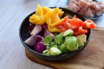 Top-down view of a bowl filled with freshly chopped vegetables, set against the background of meal preparation in a kitchen.